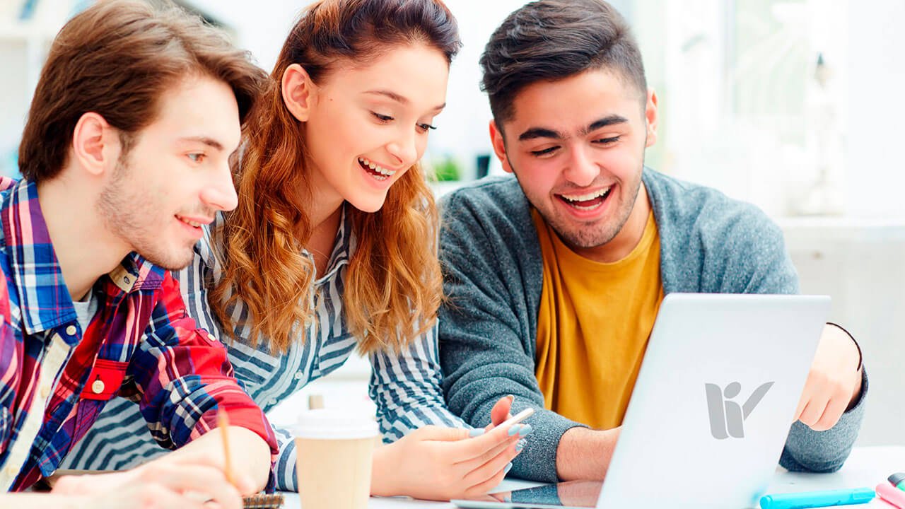 3 estudiantes universitarios mirando una laptop